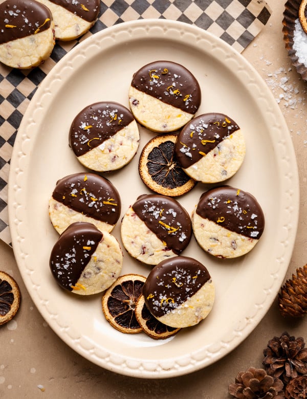 Chocolate-dipped cranberry orange shortbread cookies on platter.