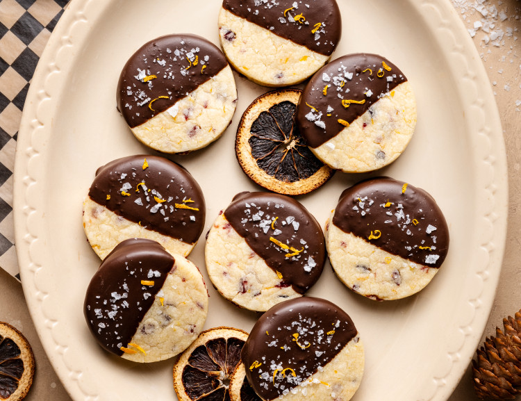 Chocolate-dipped cranberry orange shortbread cookies on platter.