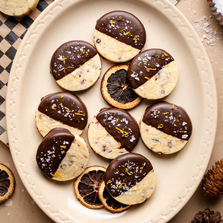 Chocolate-dipped cranberry orange shortbread cookies on platter.