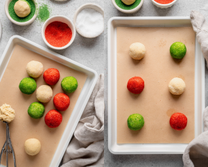 Scooping the snickerdoodle dough and rolling in colored sugars then placing on parchment-lined baking tray.