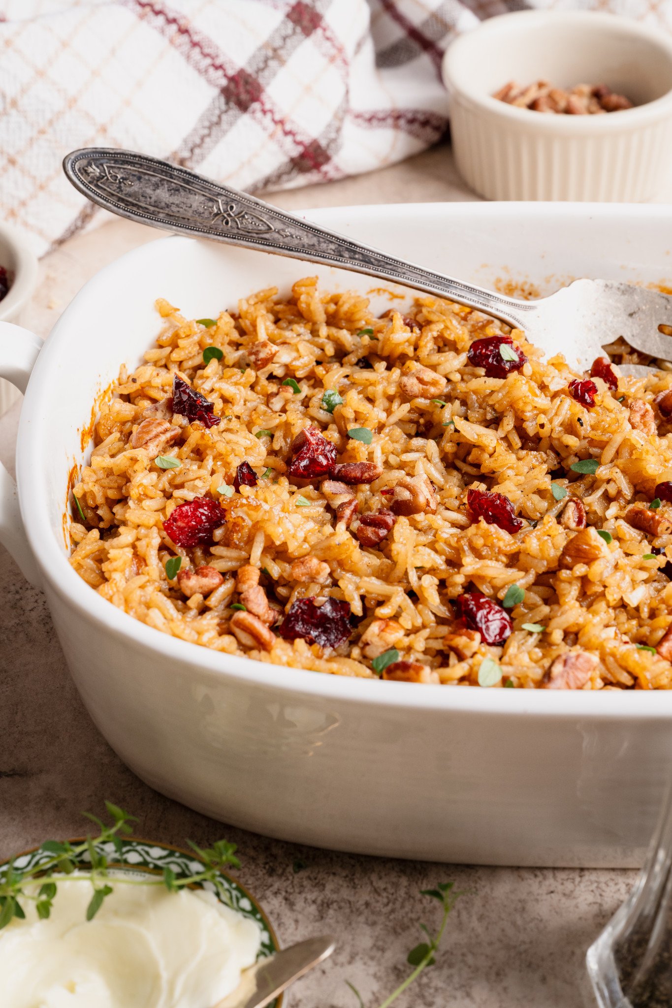 Holiday stick of butter rice in white serving dish with serving fork on the side.