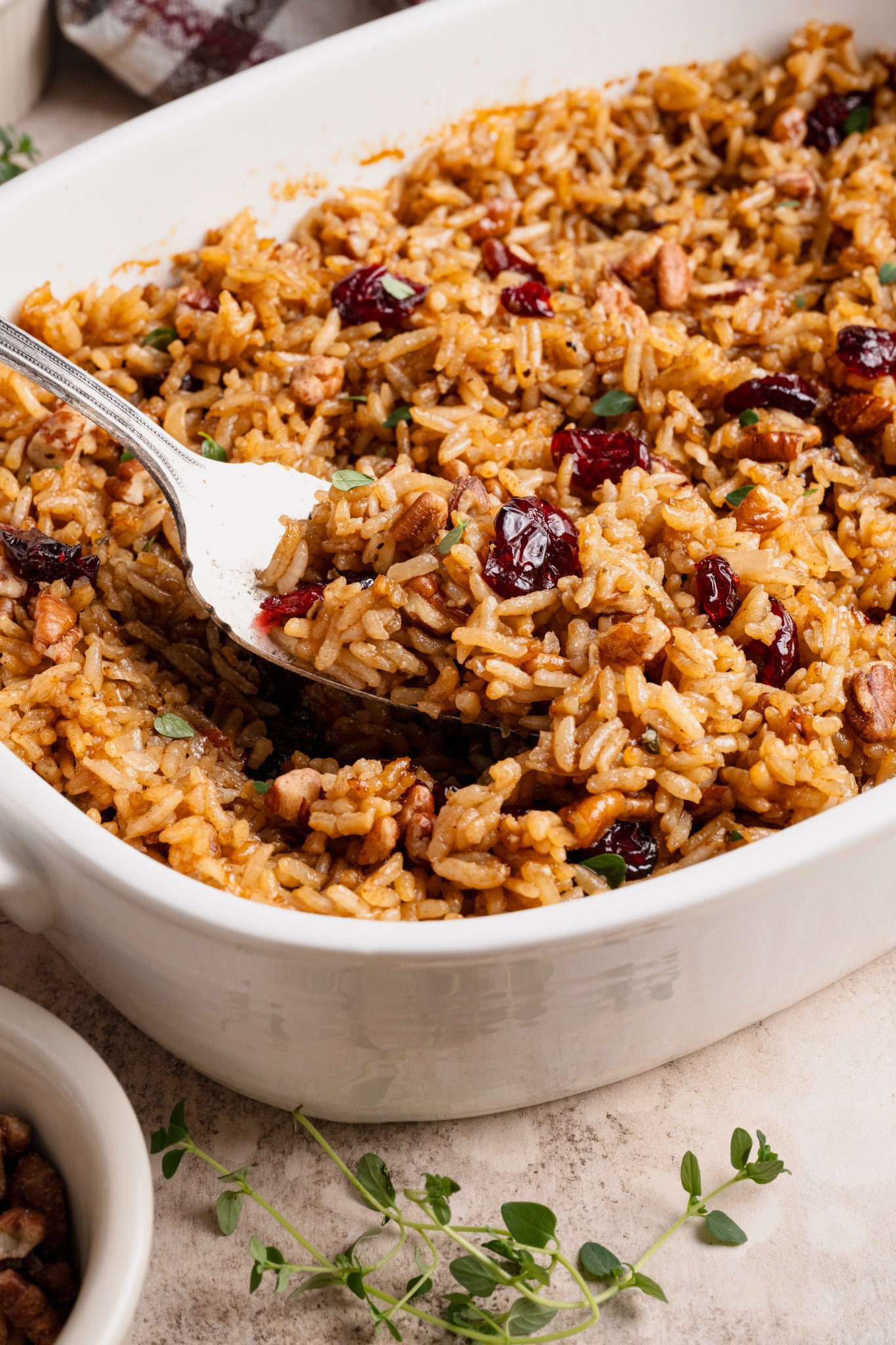 Fork holding up holiday stick of butter rice out of white serving dish.