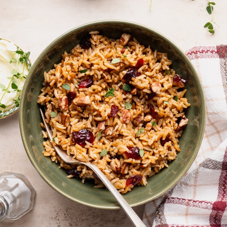 Holiday stick of butter rice recipe served in a green bowl with fork.