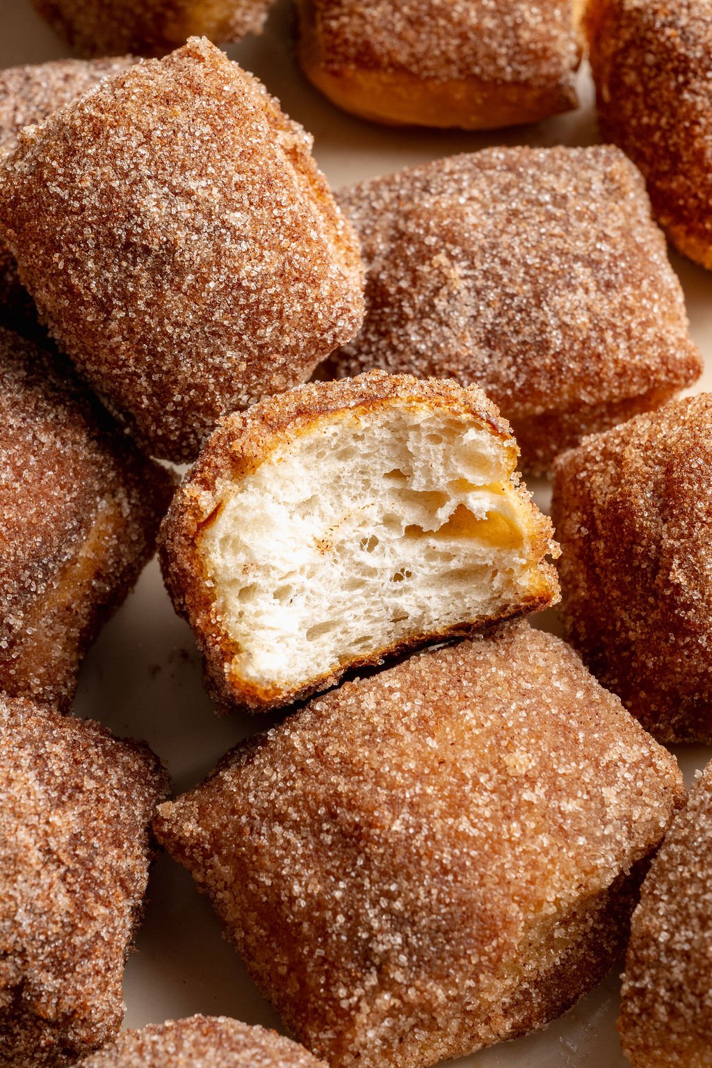 Close-up view of cinnamon sugar pretzel bites with one bite cut open to show the soft, airy interior.