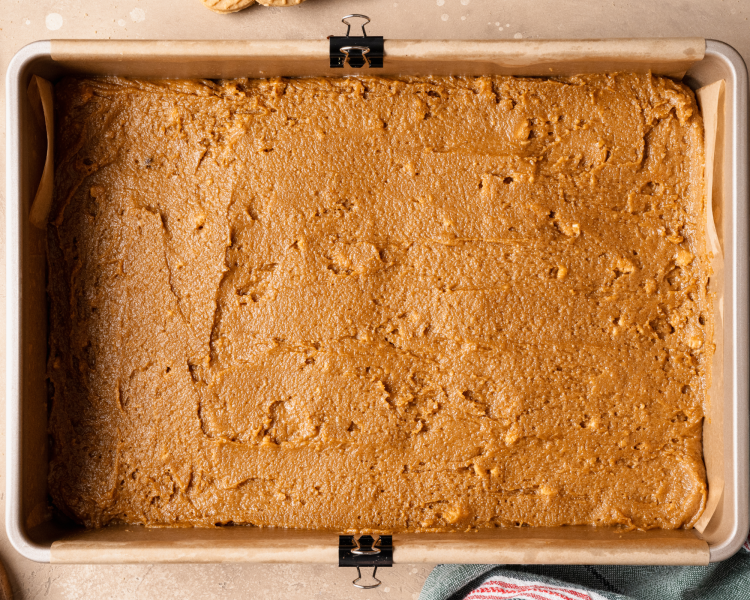 Spreading cookie bar dough into prepared 9x13 inch pan.