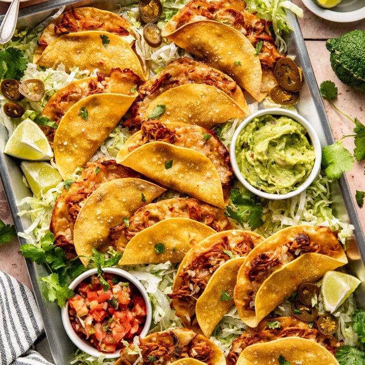 Honey chipotle chicken tacos on baking tray with lettuce, guacamole and pico.