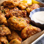 Cooked lemon pepper wings on parchment-lined baking tray.