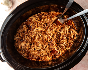 Honey chipotle chicken shredded directly in the crockpot with two forks.