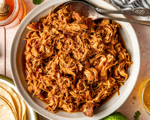 Honey chipotle chicken in a white serving dish with serving spoons on the side.
