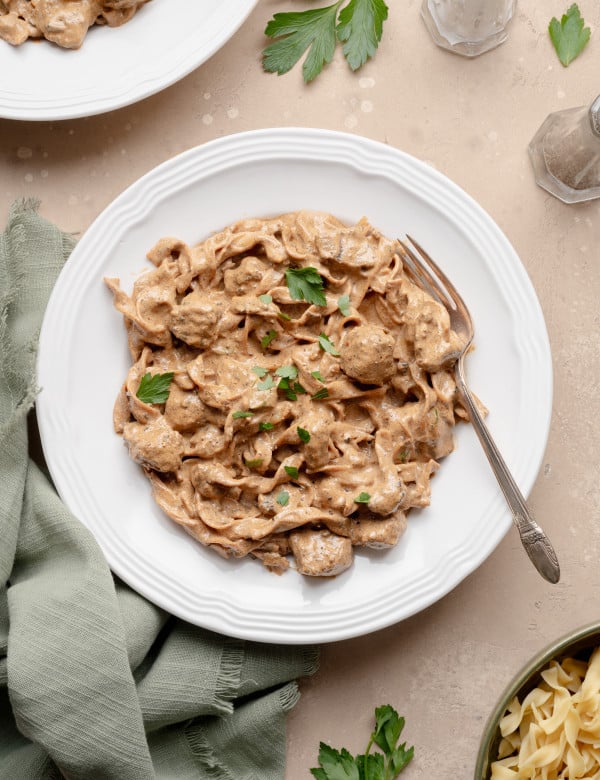 Beef stroganoff on a white plate with fork on the right side.