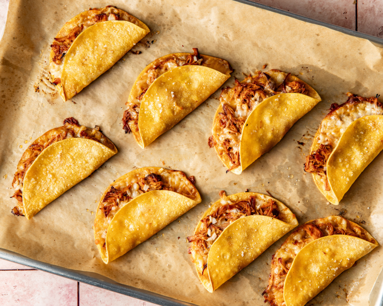 Chipotle chicken tacos baked on baking sheet with parchment paper.