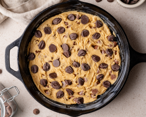 Skillet cookie dough poured into skillet and topped with super cookie chips before baking.