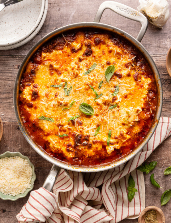 Gnocchi lasagna baked in stainless pot and garnished with fresh basil.