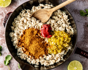 Photo showing adding the seasonings, tomato paste and diced green chiles to the cooked ground chicken.