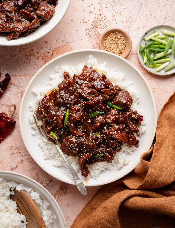 Mongolian beef served over rice on plate with fork on the side.