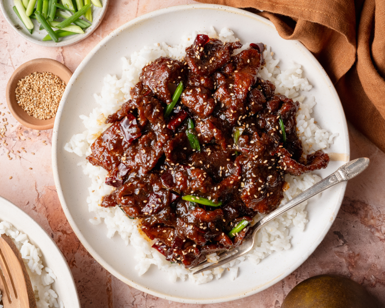 Mongolian beef plated with rice on white plate with fork.