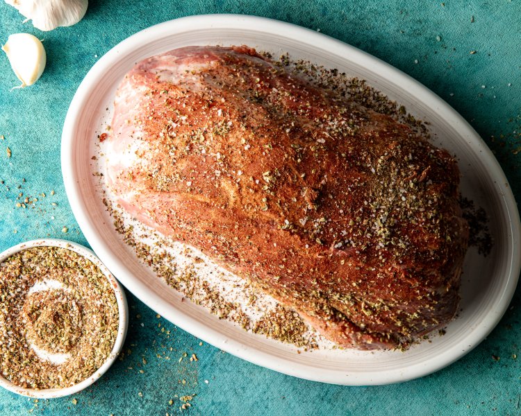 Seasoning pork shoulder with carnitas seasonings.
