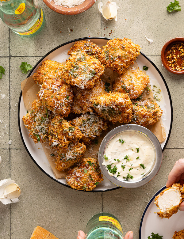 Plate of baked garlic parmesan boneless wings with a side of parmesan aioli on the side.