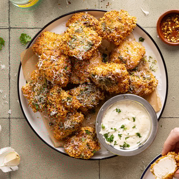 Plate of baked garlic parmesan boneless wings with a side of parmesan aioli on the side.
