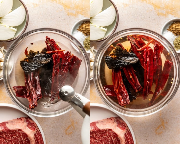 Dried chiles soaking in hot water in a glass bowl, with steam rising as the chiles soften for blending. Softened dried chiles fully submerged in hot water in a glass bowl after soaking, ready to be blended for birria sauce.