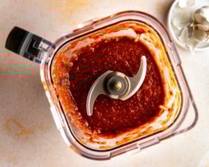 Blended birria sauce inside a blender, showing a smooth, thick, deep red chile sauce.