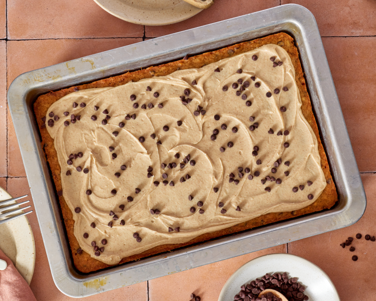 Chocolate chip banana bars cooked and cooled in a 9x13 plan with frosting on top and extra chocolate chips.