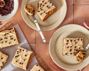 Chocolate chip banana bars sliced and served on plates with forks cutting into the corner of the bars.