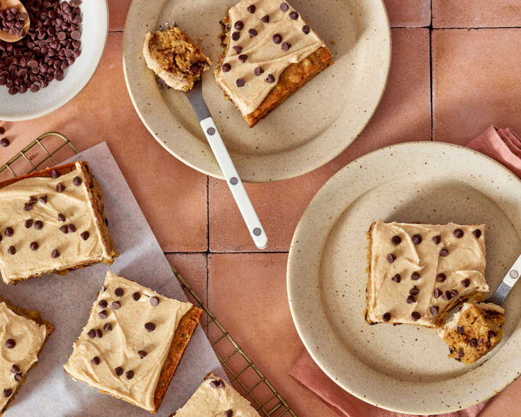 Chocolate chip banana bars sliced and served on plates with forks cutting into the corner of the bars.