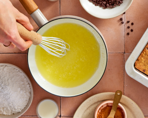Melted butter in saucepan with whisk starting to stir the butter.