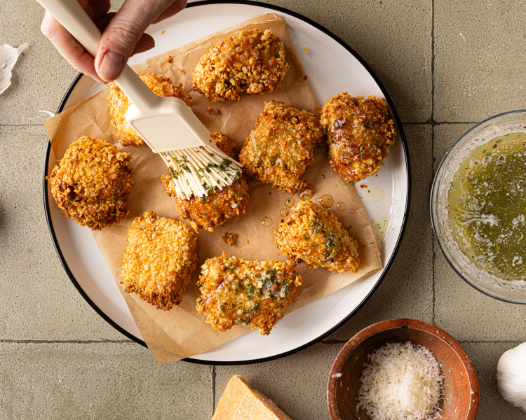 Pastry brush brushing cooked wings.