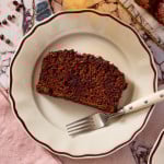 A slice of chocolate olive oil banana bread on a plate with a fork.