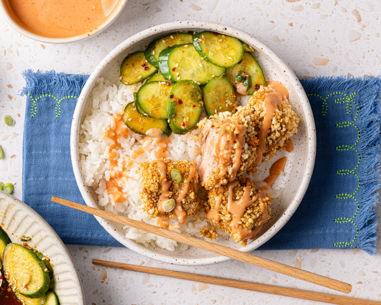 Salmon nuggets on top of rice in bowl with cucumber salad and drizzled with homemade bang bang sauce. - 12