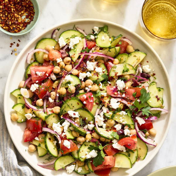 Cucumber tomato salad tossed and served on large serving plate.