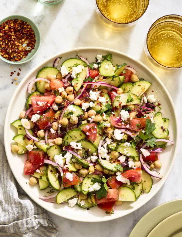 Cucumber tomato salad tossed and served on large serving plate.
