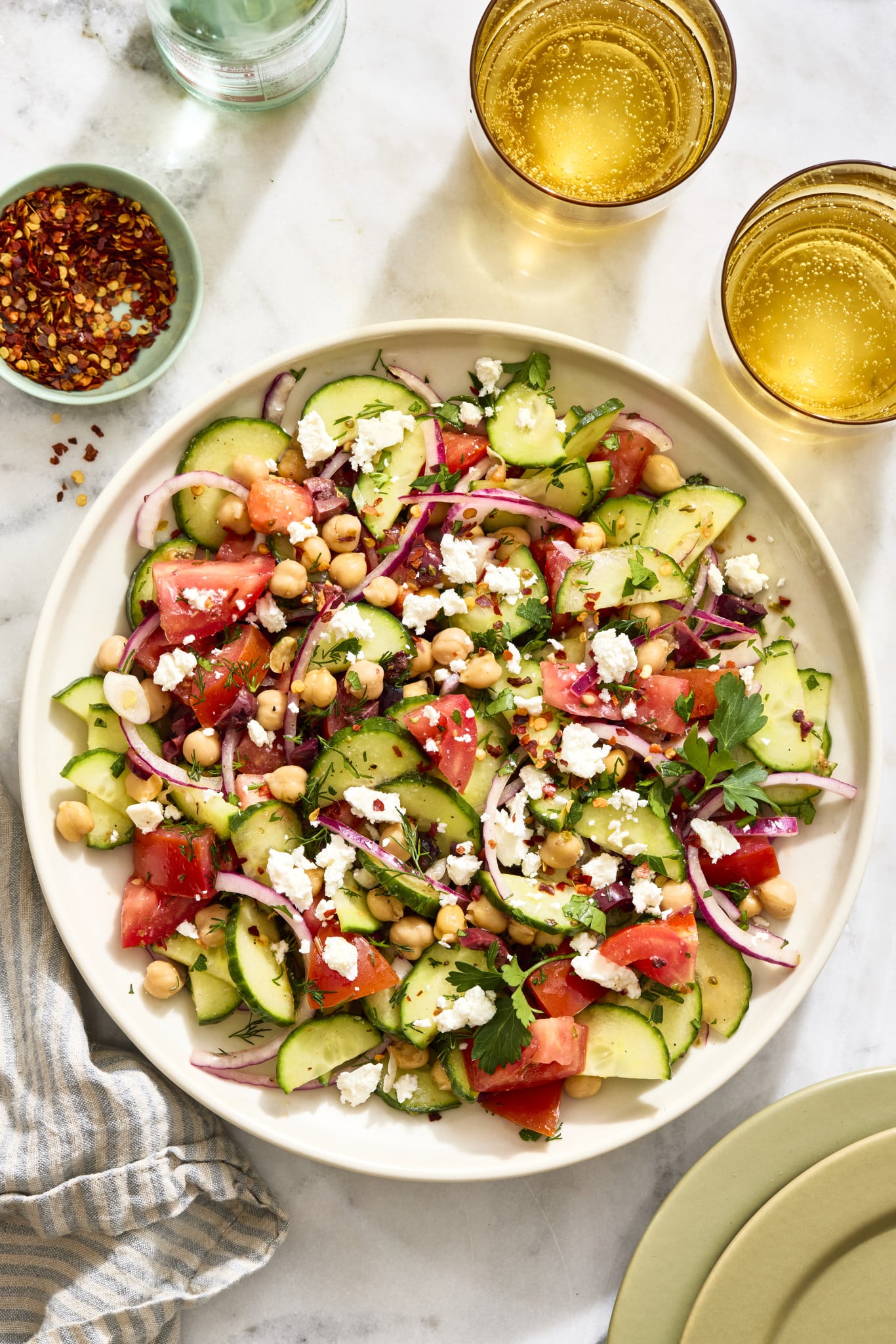 Cucumber tomato salad tossed and served on large serving plate.