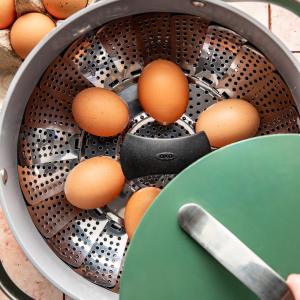 Eggs placed on a steamer in a large green pot.