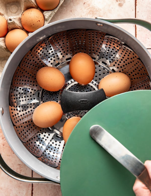 Eggs placed on a steamer in a large green pot.