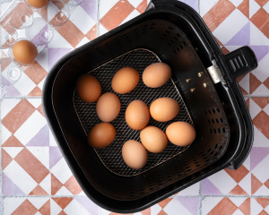 Ten brown eggs placed in a single layer in the air fryer basket.