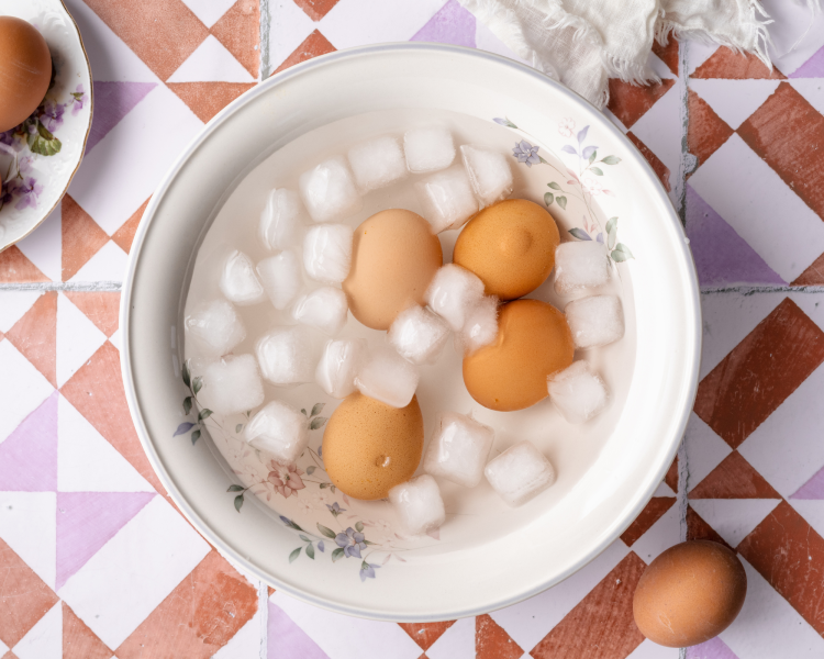 Four eggs placed in an ice bath after cooking.