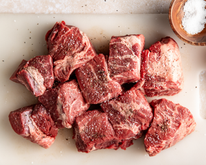 Chunks of beef cut up and seasoned with kosher salt and black pepper before searing.