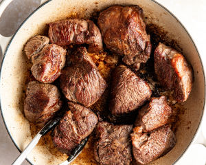 Searing chunks of beef in hot pan before adding to slow cooker.
