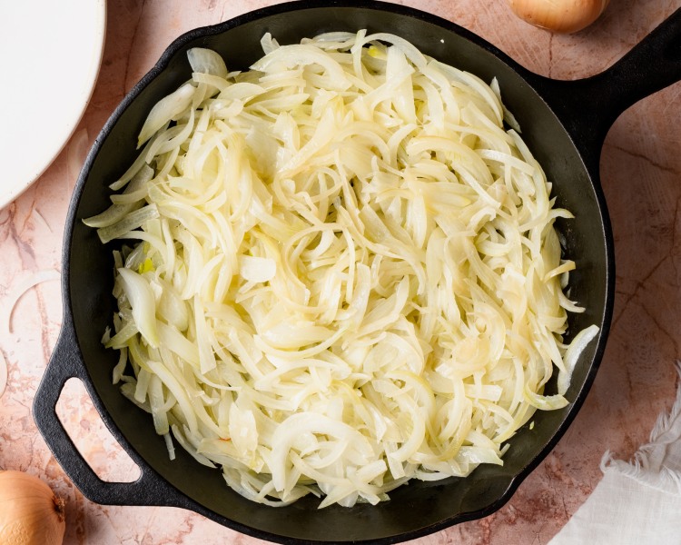 Onions cooking in a cast-iron pan.