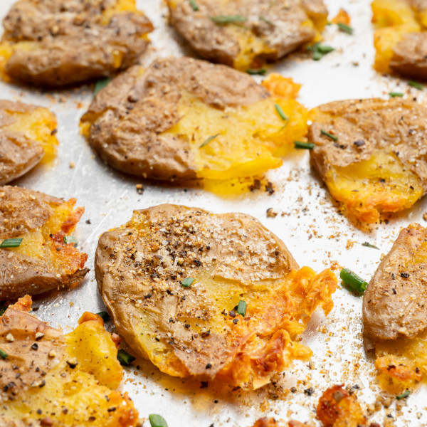 Upclose shot of crispy smashed potatoes on baking sheet.