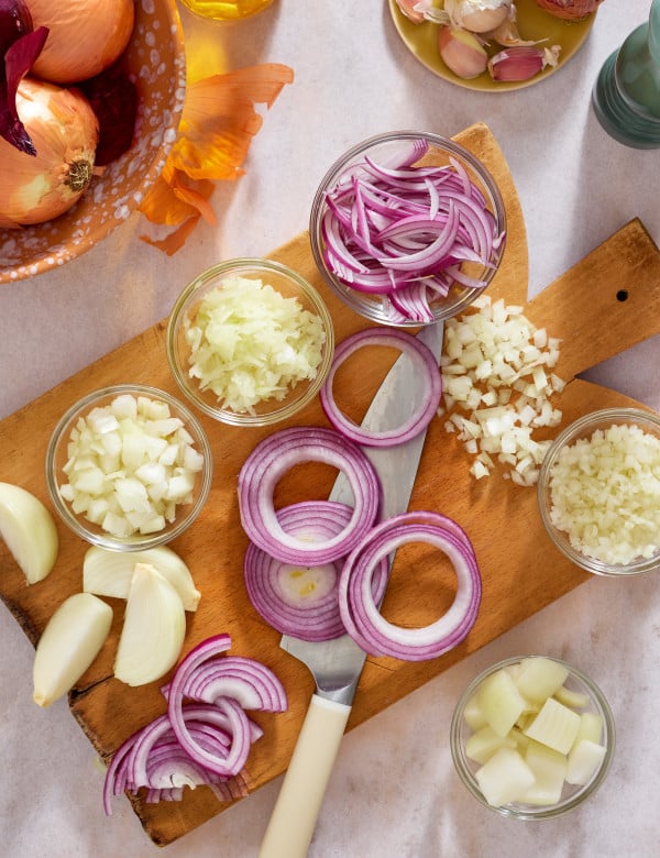All the different variations of how to cut on onion displayed on a cutting board.