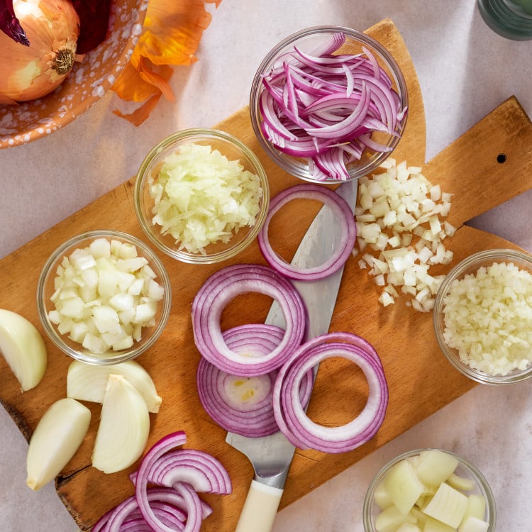 All the different variations of how to cut on onion displayed on a cutting board.