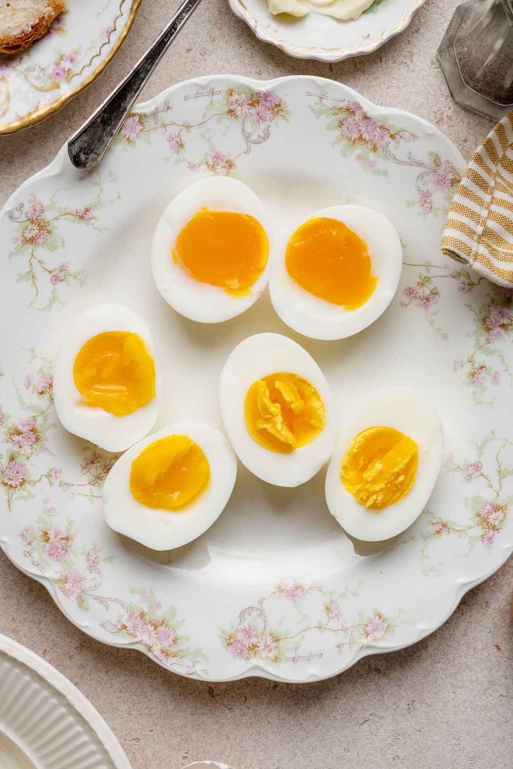 Halved Instant Pot hard boiled eggs with jammy and firm yolks arranged on a vintage floral plate.