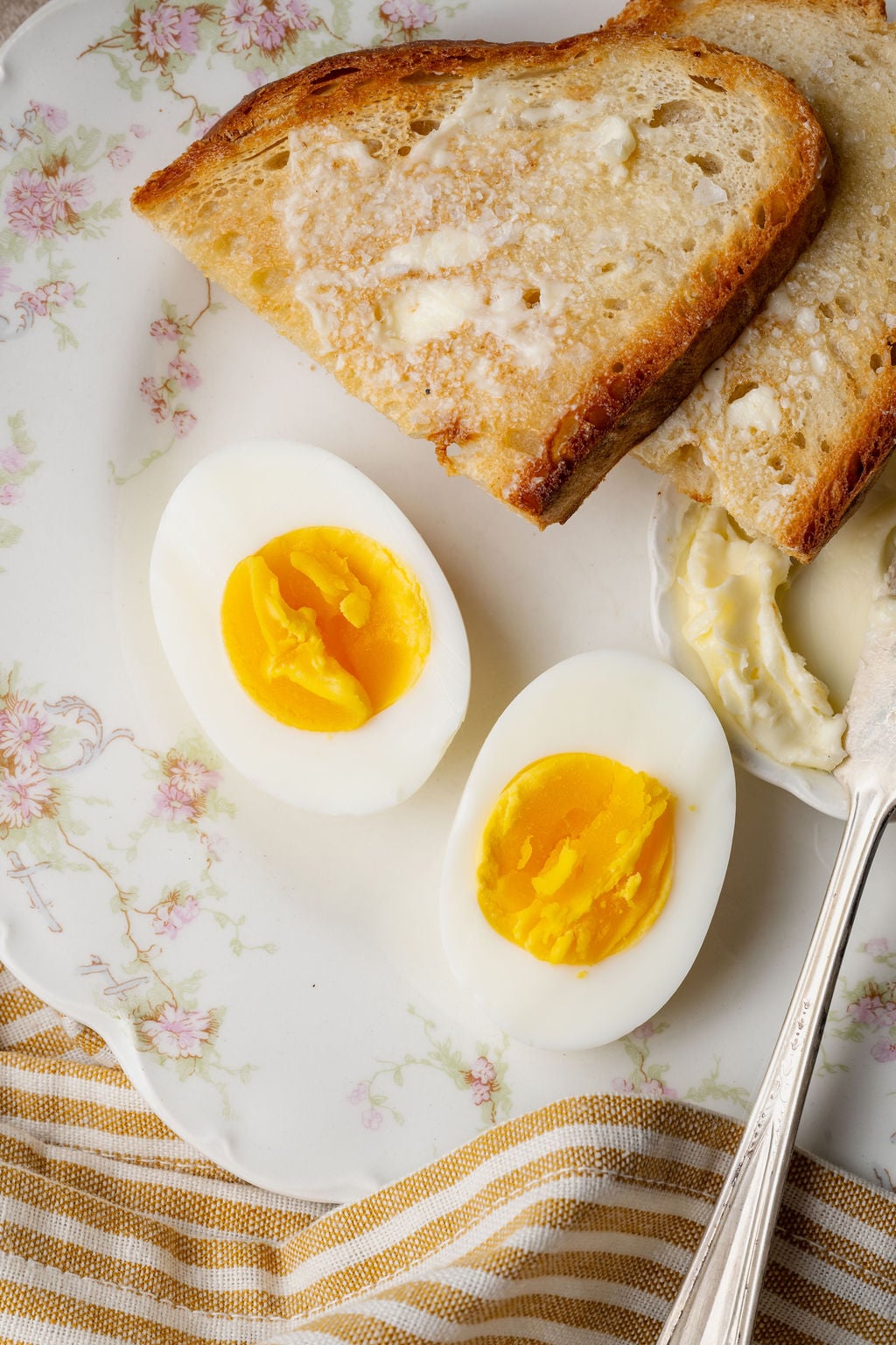 Hard boiled eggs with buttered toast on a floral plate, perfect for an easy breakfast or snack.