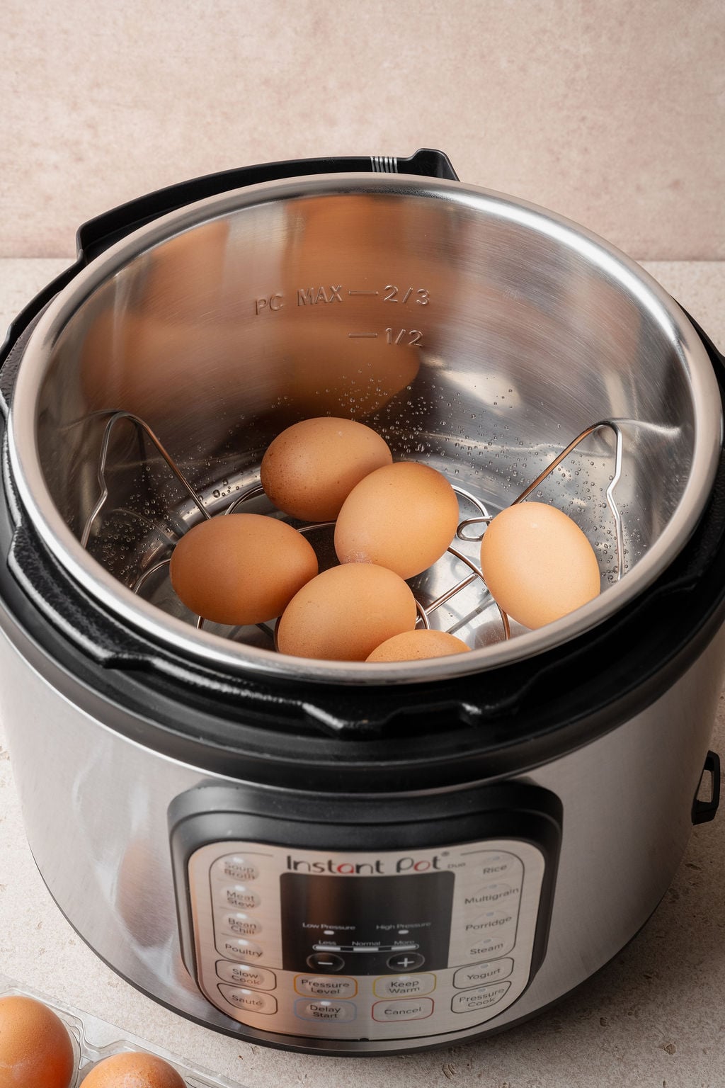 Large eggs resting on the trivet inside an Instant Pot insert before pressure cooking hard boiled eggs.