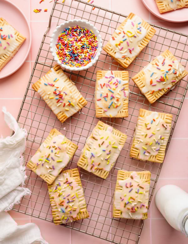Nine strawberry pop tarts setting on a wire rack.