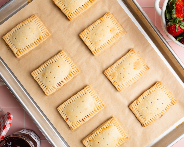 Eight pop tarts baked on baking tray lined with parchment paper.